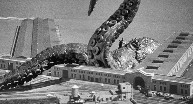 Cena do filme de monstros gigantes, O Monstro do Mar Revolto. Um polvo gigante ataca um prédio próximo ao mar
