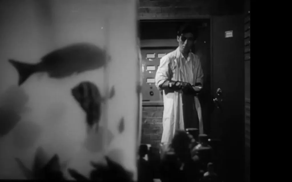 O cientista Daisuke Serizawa, personagem central no primeiro filme do Godzilla, olha para um aquário com alguns peixes que ele utiliza na sua pesquisa de desenvolvimento do Oxygen Destroyer