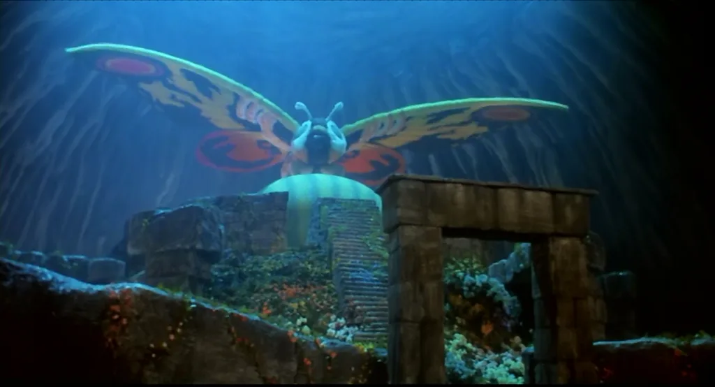 Cena do filme O Renascimento de Mothra. A imagem mostra a titular mariposa gigante Mothra no meio de uma caverna protegendo um ovo gigante