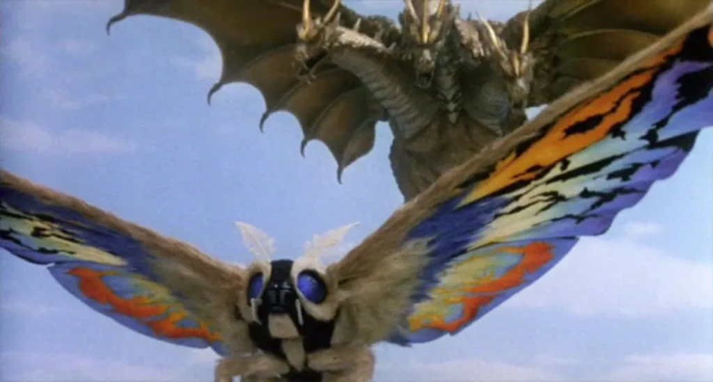 Cena de O Renascimento de Mothra 3. A titula Mothra está fugindo de Ghidorah, o dragão dourado de três cabeças, que está logo atrás dela