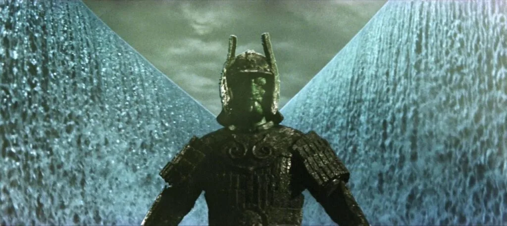 Cena do filme A Ira de Daimaji. Na imagem, o deus demônio está enquadrado no centro da tela, olhando para frente, enquanto atrás dele as águas do lago se abrem