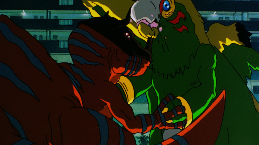 Cena do filme Digimon Adventure. Na esquerda está Greymon, um T-Rex laranja gigante com listras azuis, e na direita está Parrotmon, um papagaio gigante. Os dois disputam força segurando as mãos um dos outros enquanto Greymon finca o chifre na ponta do seu nariz no bico de Parrotmon