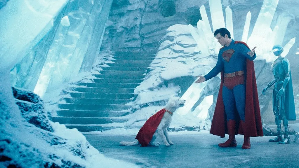 Cena do filme de Superman (2025) dirigido pelo James Gunn. Superman está na Fortaleza da Solidão brigando com Krypto enquanto um dos seus robôs os observam