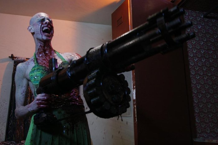 Madame Úrsula, personagem de Mar Negro, segurando uma metralhadora gigante