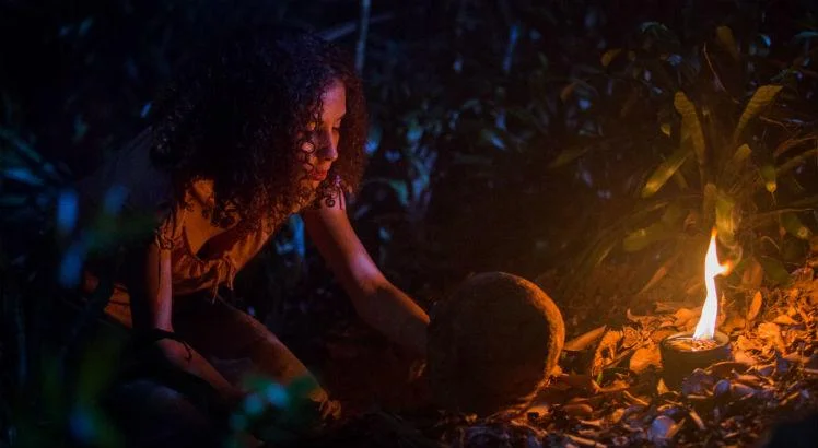 Cena de A Mata Negra onde a personagem Clara faz um ritual para amaldiçoar um dos himens que tentou matá-la e roubou seu dinheiro